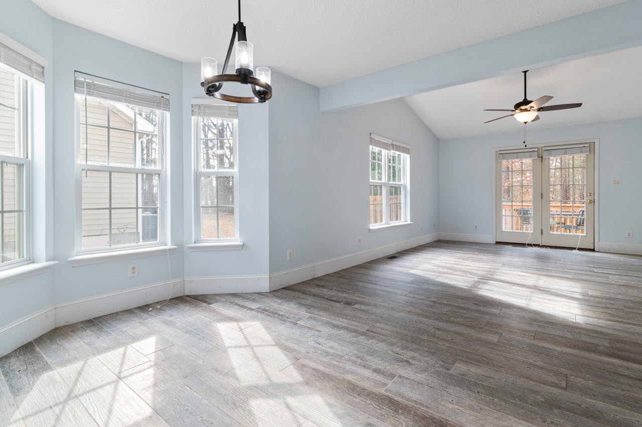 Bright empty living room with wooden floor and ceiling fan, ideal for interior design use.